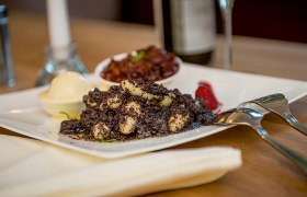 Mohnnudeln, © Waldviertel Tourismus, Studio Kerschbaum Ein Teller mit Mohnnudeln, garniert mit Mohn und einer Beilage, auf einem Tisch serviert.