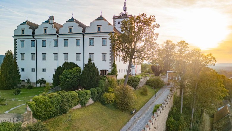 Schloss Weitra mit Sonnenuntergang, © Benjamin Wald Schloss Weitra bei Sonnenuntergang mit Garten und Bäumen im Vordergrund.