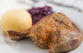 Martinigansl, © A_Lein – stock.adobe.com Ein Teller mit gebratener Gänsekeule, Kartoffelknödel und Rotkraut.