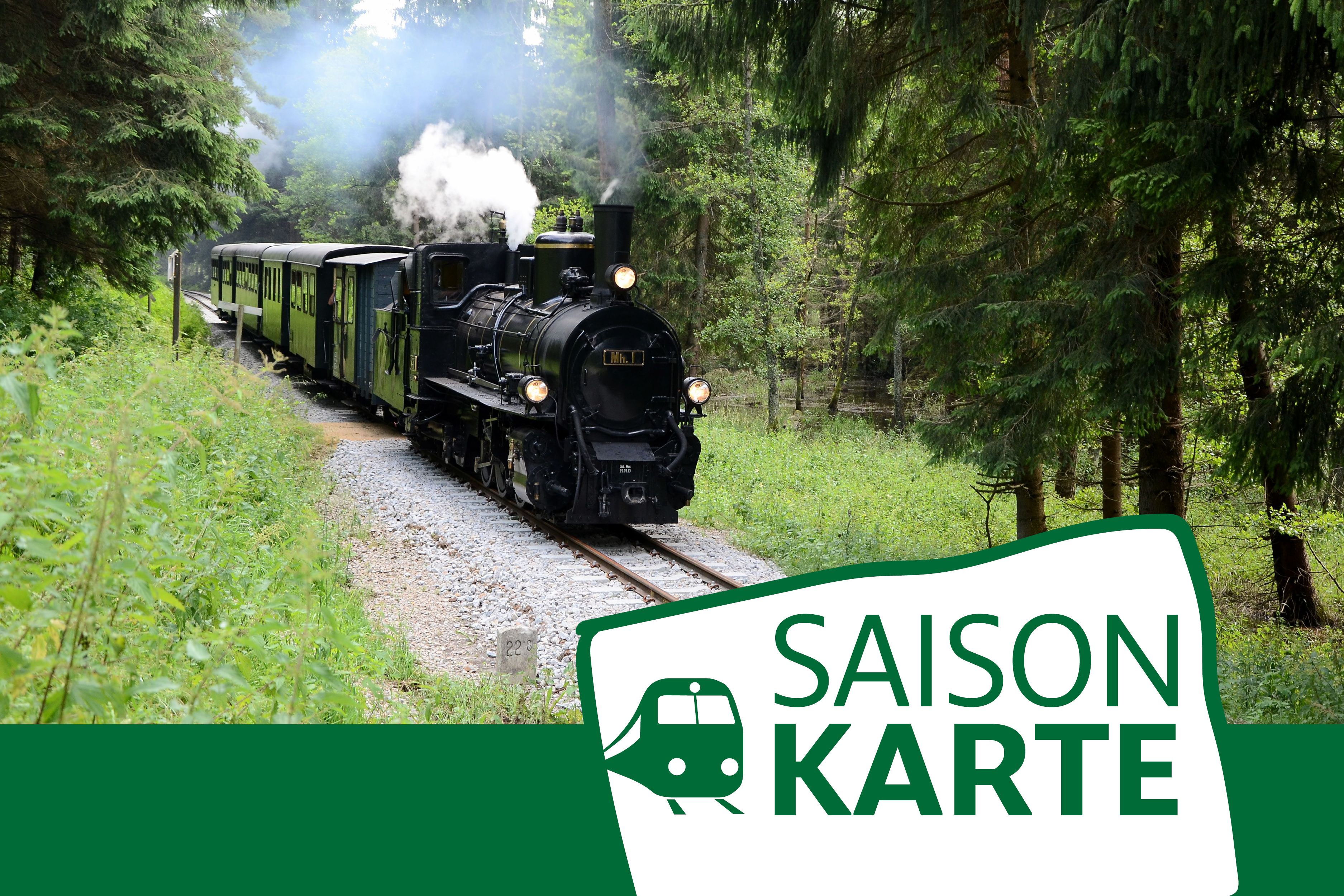 Dampflok fährt durch einen Wald, begleitet von einem Schild mit der Aufschrift 'Saisonkarte'.