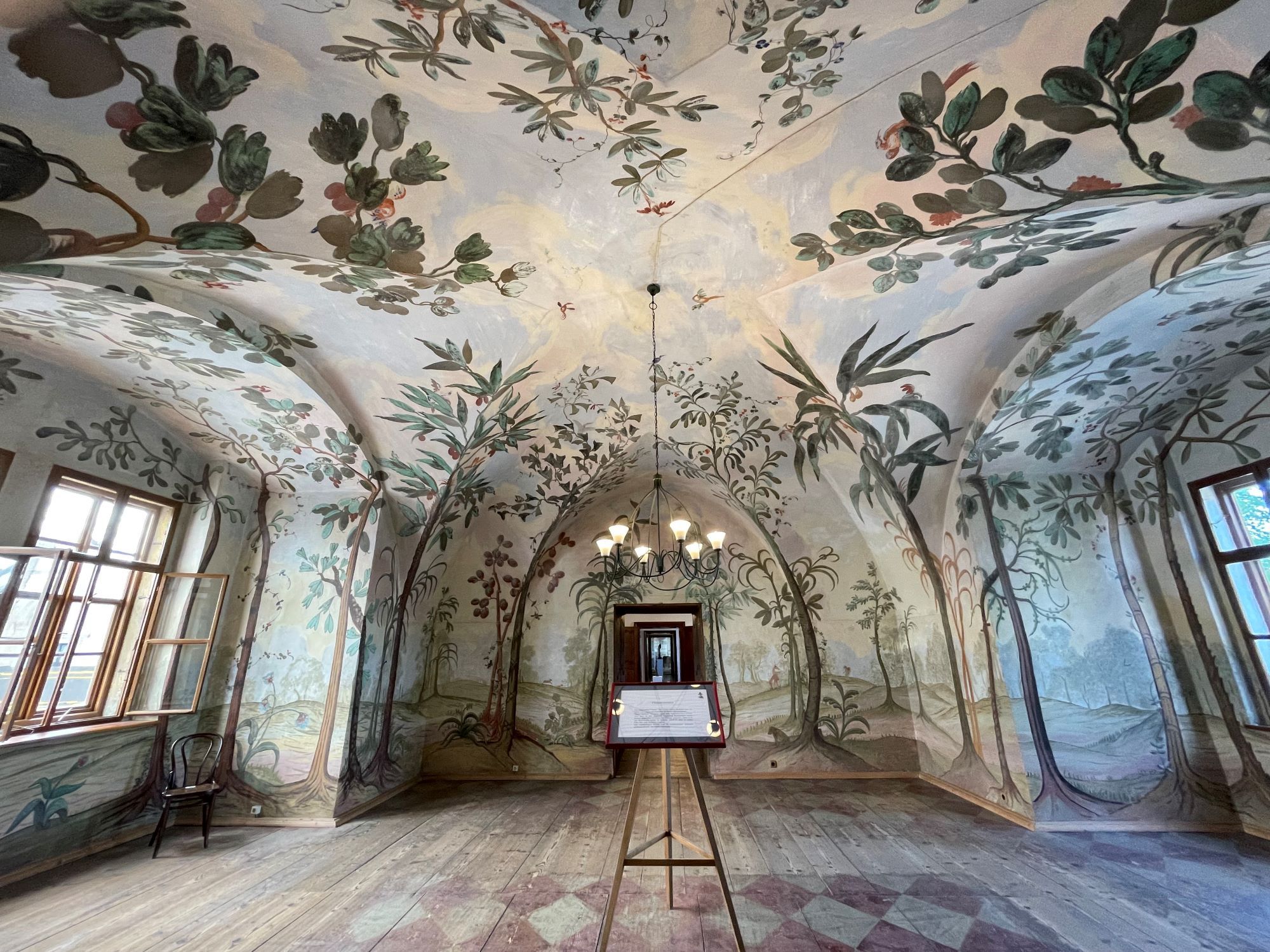 Ein kunstvoll bemalter Raum mit gewölbter Decke und floralen Motiven an den Wänden.