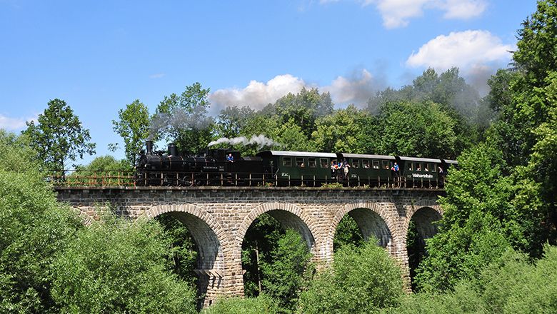 Dampfzug fährt über ein Viadukt