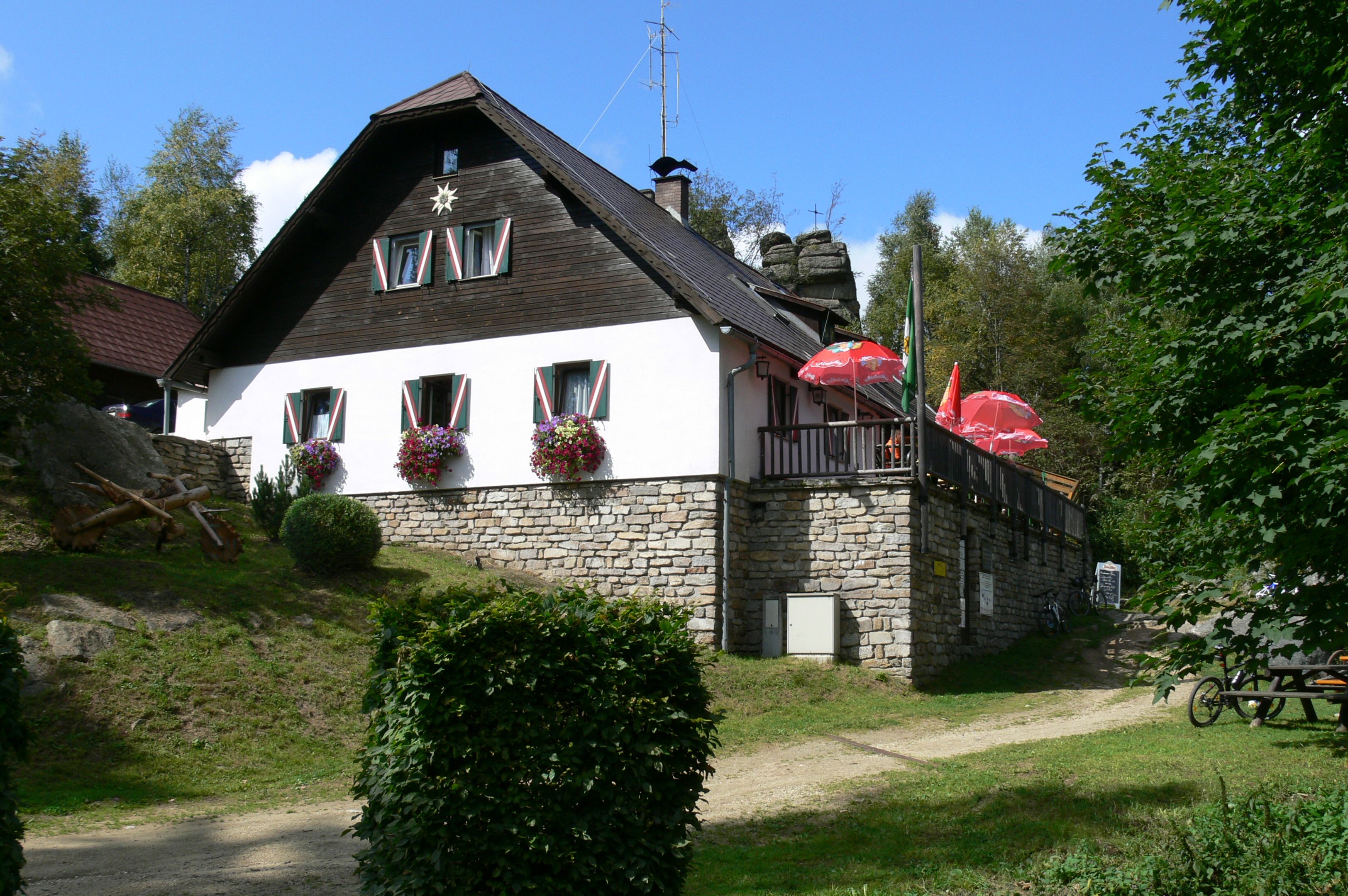 Eine Berghütte mit Blumen und Sonnenschirmen auf einer Terrasse.