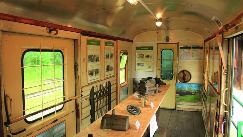 Innenraum eines historischen Eisenbahn-Museumswaggons mit Schautafeln und ausgestellten Bahnteilen.