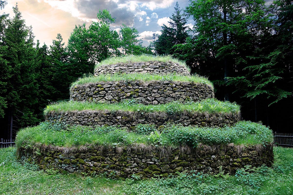 Steinpyramide in der Kraftarena Groß Gerungs, umgeben von Bäumen.