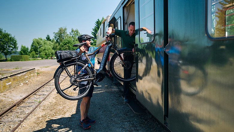 Schaffner hilft Fahrradfahrer beim verladen seines Rades