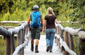 zwei Wanderer gehen über eine Brücke