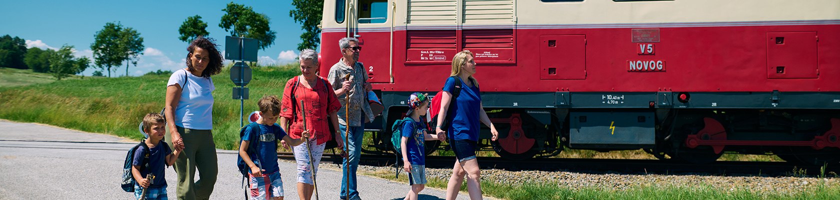 Familie mit Kindern wandert an Zug vorbei