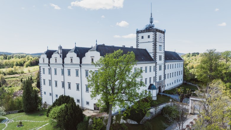 Weitra Castle with garden and tower, surrounded by trees and countryside.
