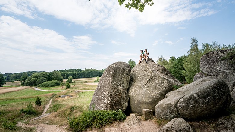 Mann und Frau sitzen auf Wackelsteinen in Gmünd auf der Blockheide