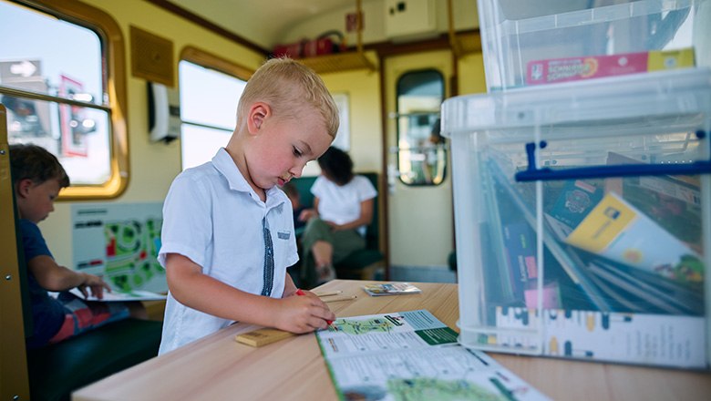 Kind zeichnet im Zug in einem Malbuch