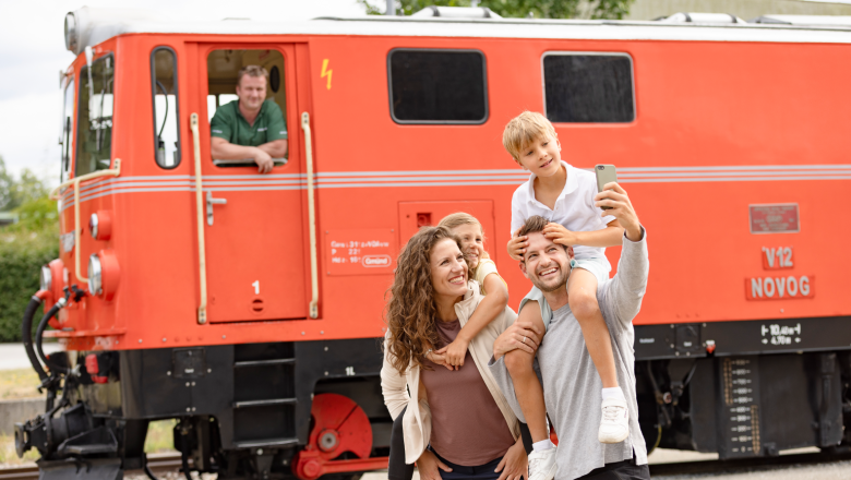 Mutter und Vater mit Sohn und Tochter machen ein Selfie vor der Lok