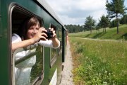 Frau sieht aus dem Waggon der Waldviertelbahn hinaus und fotografiert.