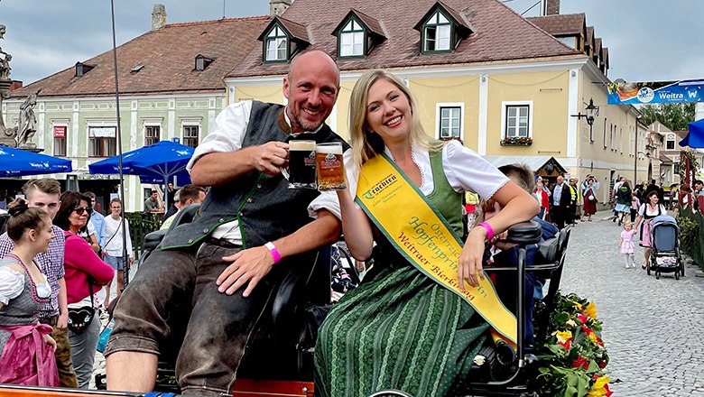 Ein Mann und eine Frau in traditioneller Tracht sitzen auf einer Kutsche beim Bierkirtag in Weitra.