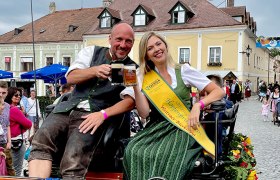 Ein Mann und eine Frau in traditioneller Tracht sitzen auf einer Kutsche beim Bierkirtag in Weitra.